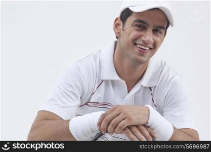Portrait of happy male tennis player with racket isolated over gray background
