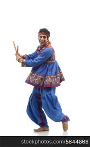 Portrait of happy man in kedia and dhoti performing Dandiya Rass isolated over white background