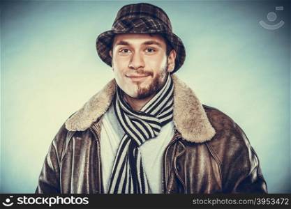 Portrait of happy man with half shaved face beard hair in hat, scarf and jacket. Smiling handsome guy on blue. Skin care hygiene and fashion. Instagram cross filter.
