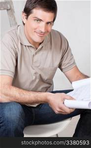 Portrait of happy mature man holding a blueprint plan in his hand