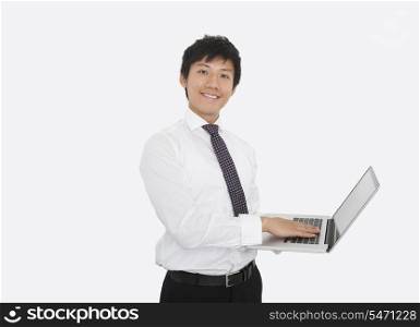 Portrait of happy mid adult businessman using laptop over white background
