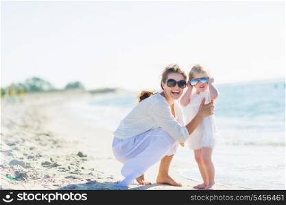 Portrait of happy mother and baby in sunglasses on beach