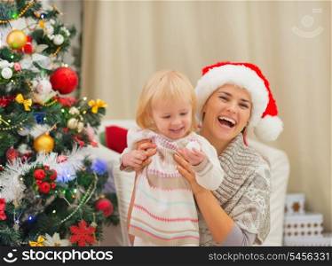 Portrait of happy mother and baby near Christmas tree