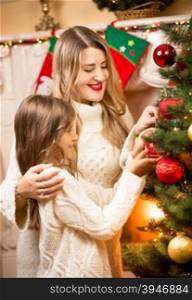 Portrait of happy mother and daughter decorating Christmas tree at house