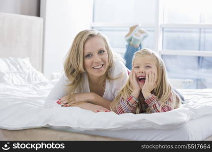 Portrait of happy mother and daughter lying in bed