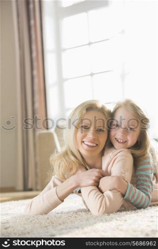 Portrait of happy mother and daughter lying on floor at home