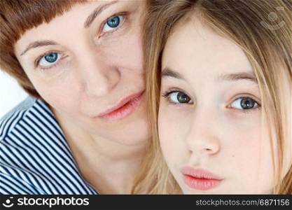 Portrait of happy mother and daughter near white wall