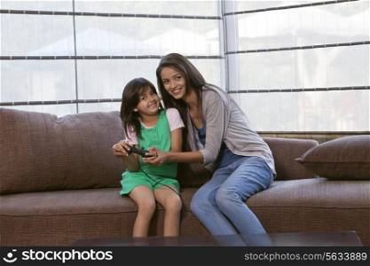 Portrait of happy mother and daughter playing video game together at home