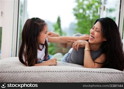 Portrait of happy mother and her daughter playing on couch