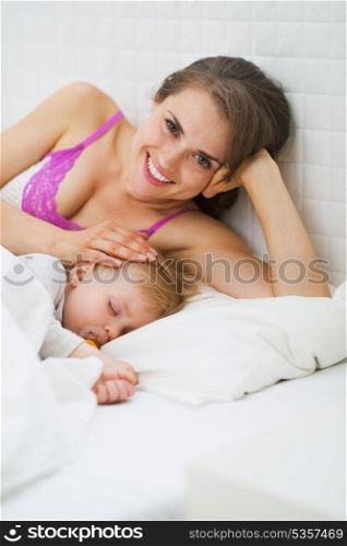 Portrait of happy mother and sleeping baby