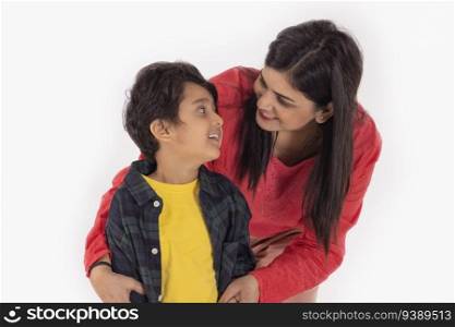 Portrait of happy mother and son looking at each other against white background