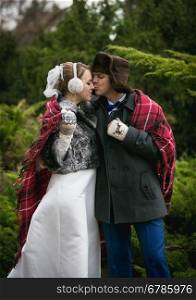 Portrait of happy newly married couple kissing at winter forest