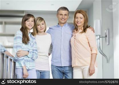 Portrait of happy parents with daughters standing together at home