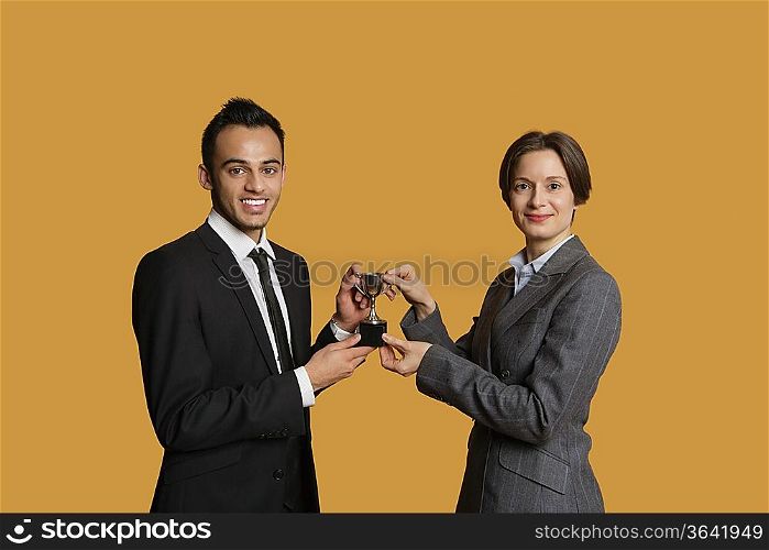 Portrait of happy partners holding winning trophy together