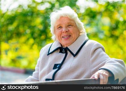 portrait of happy pensioner sitting on a bench in the park