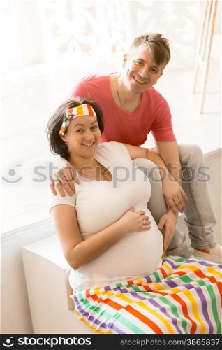 Portrait of happy pregnant couple hugging and looking at camera