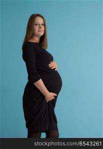 Portrait of happy pregnant woman with hands on belly isolated over blue background. Portrait of pregnant woman over blue background