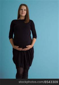 Portrait of happy pregnant woman with hands on belly isolated over blue background. Portrait of pregnant woman over blue background