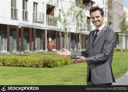 Portrait of happy real estate agent presenting office building