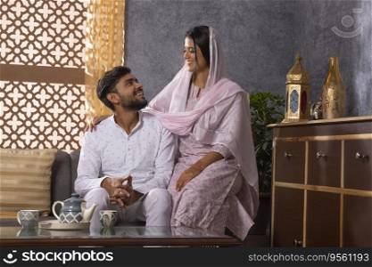 Portrait of happy romantic Muslim couple sitting together in living room