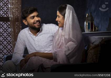 Portrait of happy romantic Muslim couple sitting together in living room