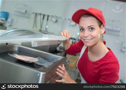 portrait of happy saleswoman holding meat packages at counter