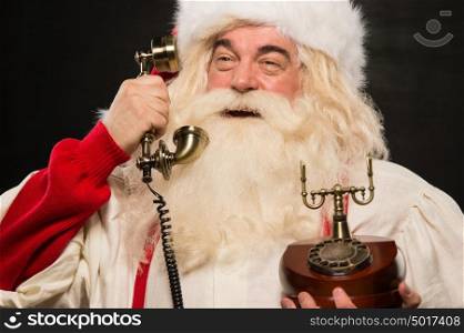 Portrait of happy Santa Claus calling phone against dark background