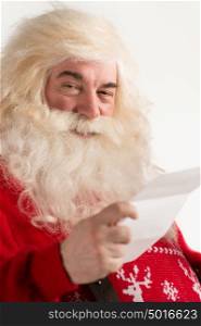 Portrait of happy Santa Claus holding Christmas letter and looking at camera