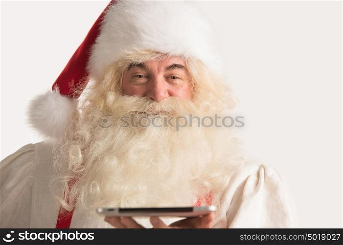 Portrait of happy Santa Claus holding tablet computer in his hands and looking at camera
