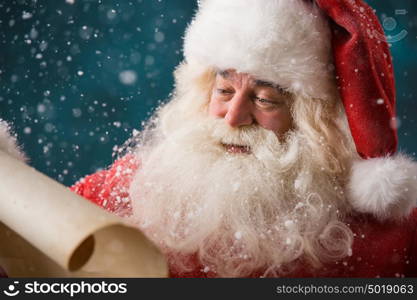 Portrait of happy Santa Claus reading Christmas letter outdoors at north pole at snowfall