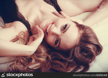 Portrait of happy seductive woman wearing lingerie in bed at home. Attractive sensual smiling young girl with long hair. Female underwear fashion.. Portrait of happy young woman in lingerie in bed.
