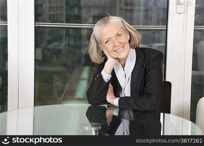 Portrait of happy senior businesswoman sitting at table