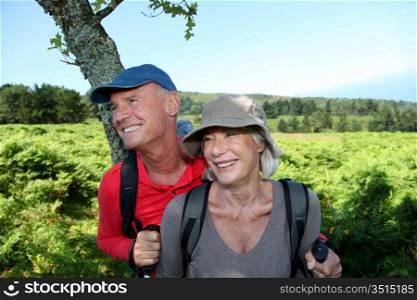 Portrait of happy senior couple hiking in natural landscape