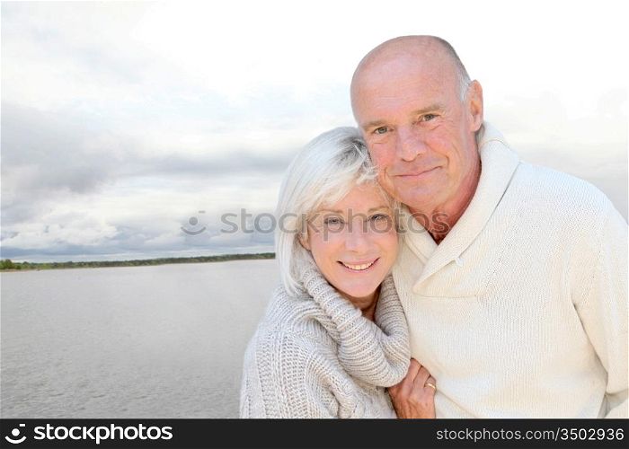 Portrait of happy senior couple standing by a lake