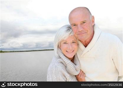 Portrait of happy senior couple standing by a lake