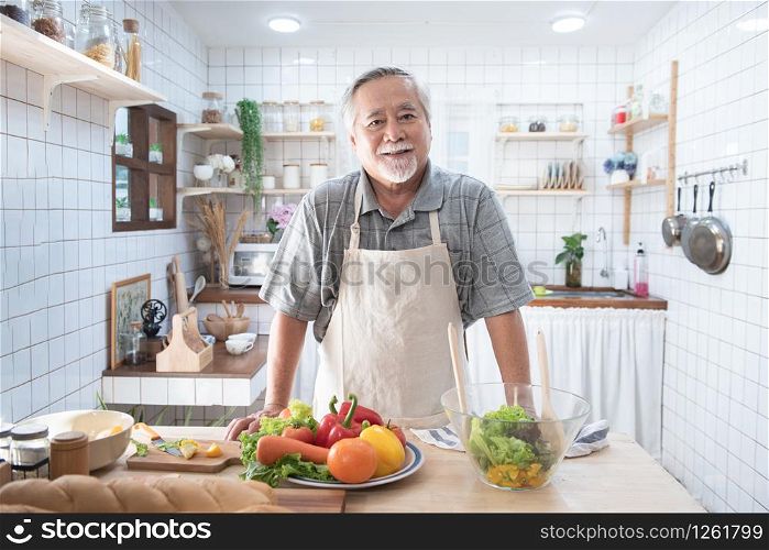 Portrait of happy senior elderly asian grandfather standing cooking meal in kitchen,Old men prepare dinner in hobby lifestyle.