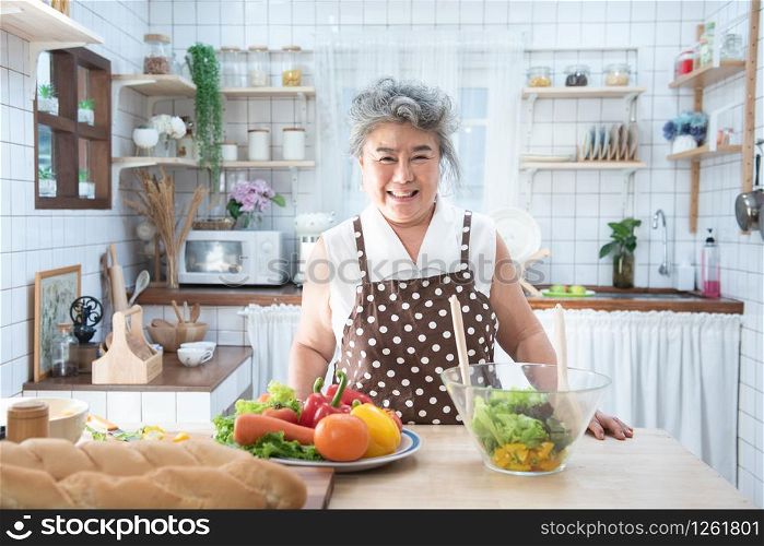Portrait of happy senior elderly asian grandmother standing cooking meal in kitchen,Old women prepare dinner in hobby lifestyle.