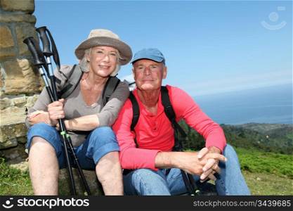 Portrait of happy senior hikers resting by stone house