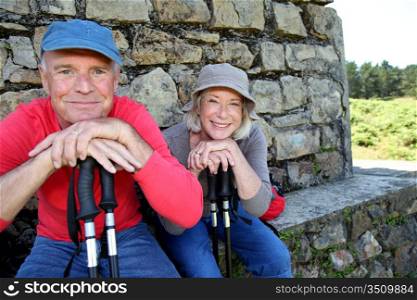 Portrait of happy senior hikers resting by stone house