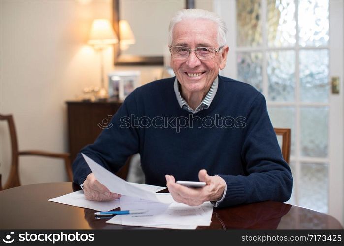 Portrait Of Happy Senior Man Reviewing Domestic Finances