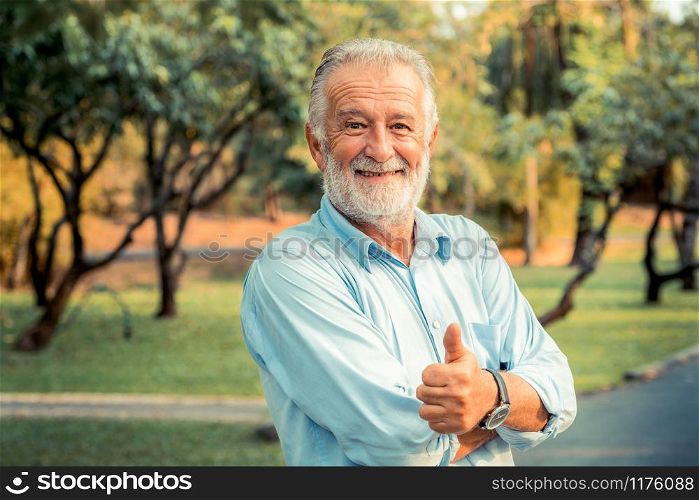 Portrait of happy senior man standing in the park. Elder health and retirement concept.