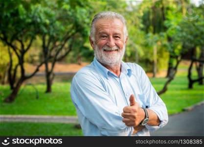 Portrait of happy senior man standing in the park. Elder health and retirement concept.. Portrait of happy senior man standing in the park.