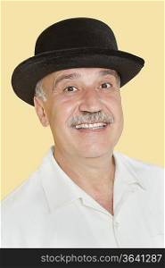 Portrait of happy senior man with black hat over yellow background