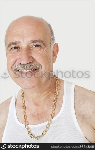 Portrait of happy senior man with gold chain over gray background