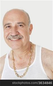 Portrait of happy senior man with gold chain over gray background