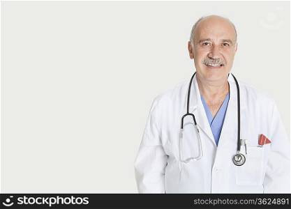 Portrait of happy senior medical practitioner over gray background