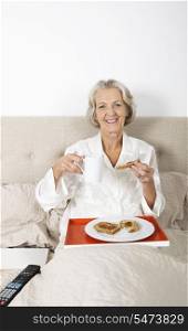 Portrait of happy senior woman having breakfast in bed