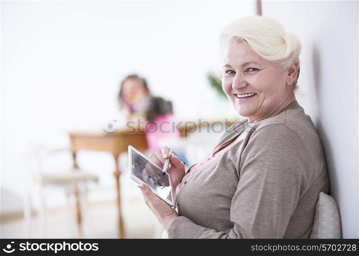 Portrait of happy senior woman using digital tablet with stylus at home