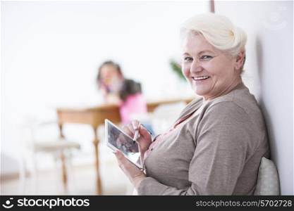 Portrait of happy senior woman using digital tablet with stylus at home