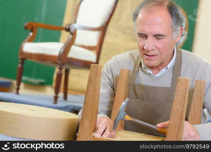portrait of happy senior worker sitting in his workshop
